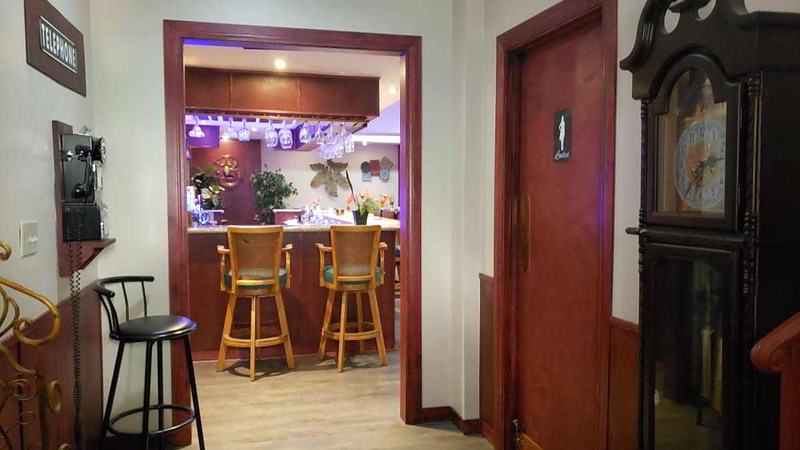 Ladies' room entrance beside the bar, with a payphone and grandfather clock