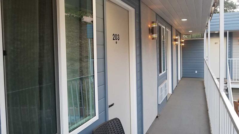 Motel second-floor walkway with room doors and a white railing