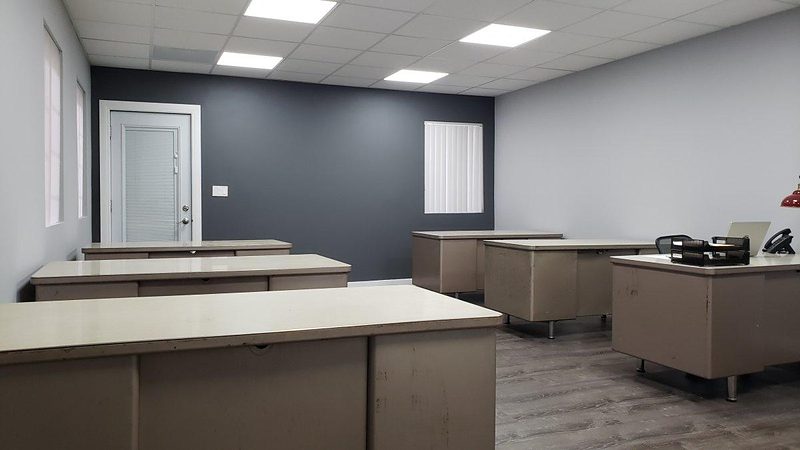 Bullpen office with seven tanker desks and a dropped-grid ceiling