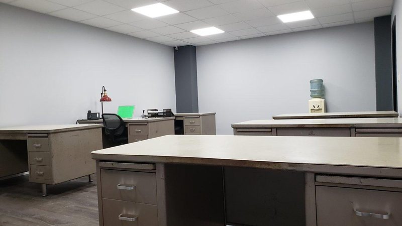 Rear view of the bullpen office with tanker desks and a water cooler
